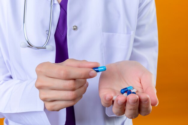 Side view of female hands with pills on isolated orange