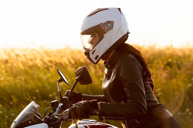 Side view female motorcycle rider with helmet