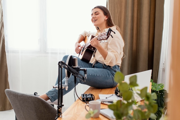 Side view of female musician at home playing acoustic guitar and singing