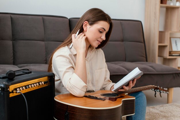 Side view of female musician with acoustic guitar writing songs