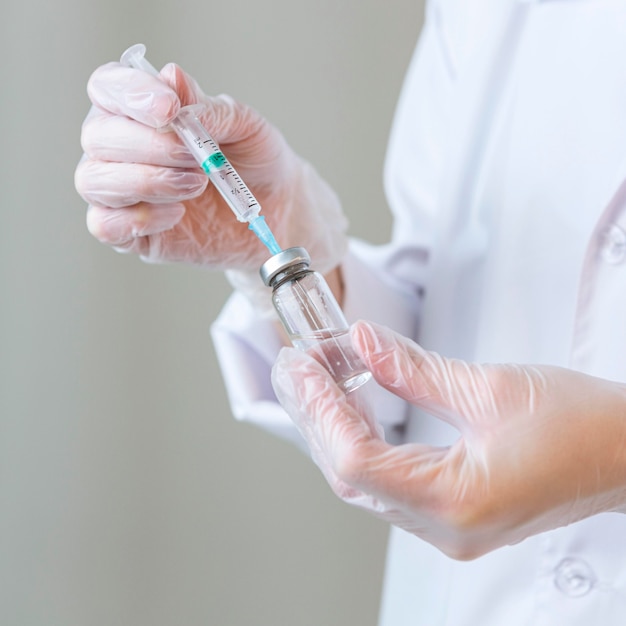 Side view of female researcher with gloves holding syringe