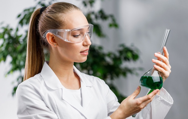 Side view of female researcher with test tube and safety glasses