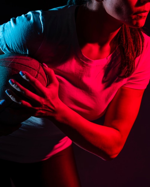 Foto gratuita vista laterale della sfera femminile della holding del giocatore di rugby