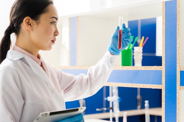 Free photo side view of female scientist holding tablet and substance