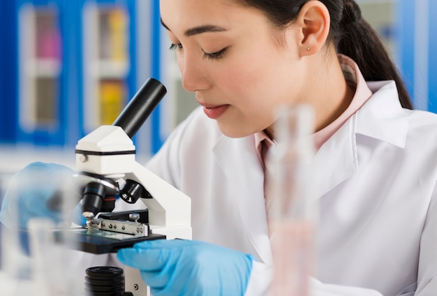 Side view of female scientist looking through microscope
