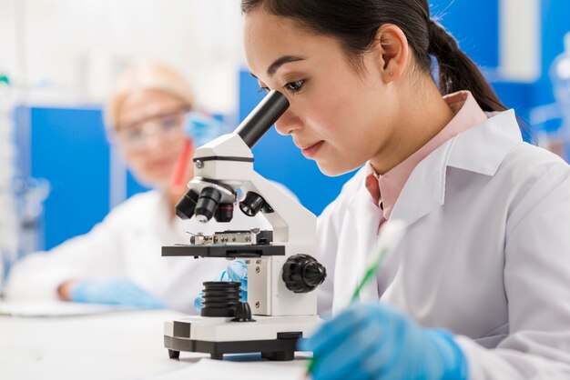研究室で顕微鏡を使って女性科学者の側面図