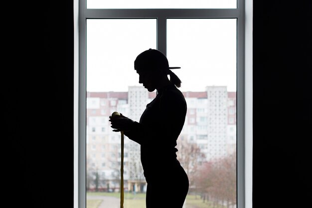 Side view of female silhouette next to window with elastic cord