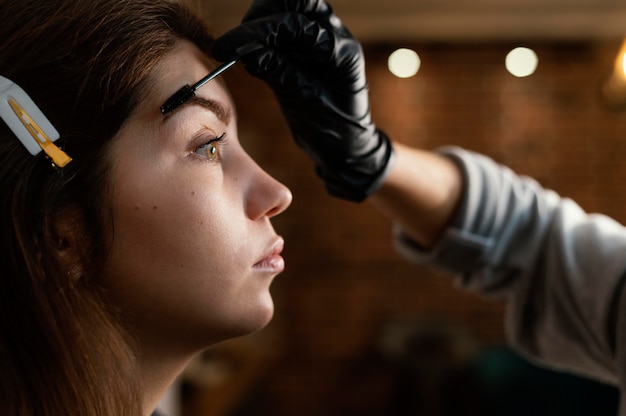 Side view of female specialist doing an eyebrow treatment for woman