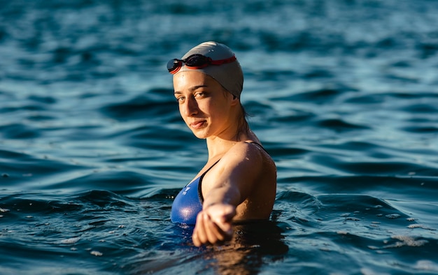 Side view of female swimmer with cap and goggles posing while swimming in water