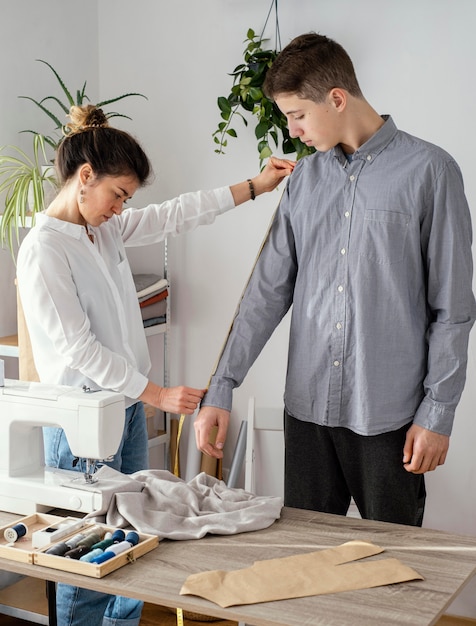 Side view of female tailor measuring male clients' shirt