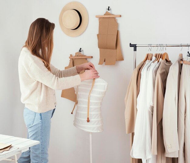 Side view of female tailor in the studio with clothes