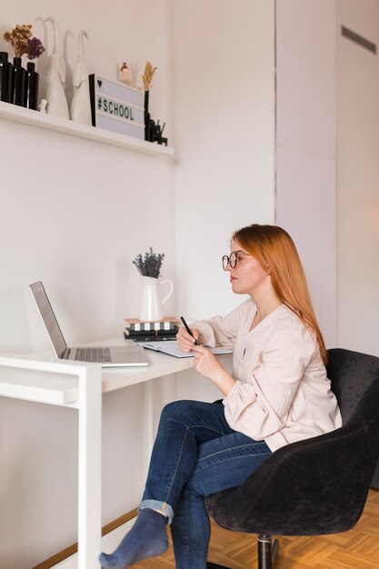 Side view of female teacher at desk during online class