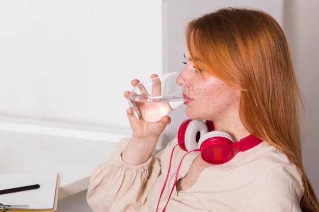 Питьевая вода учителя-женщина, вид сбоку во время онлайн-класса