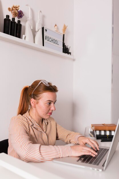 Side view of female teacher using laptop during online class