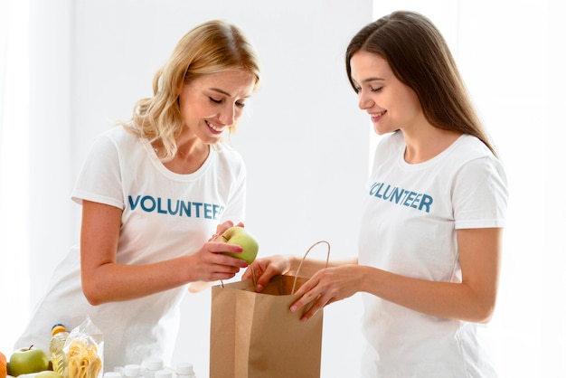 Side view of female volunteers preparing food for donation