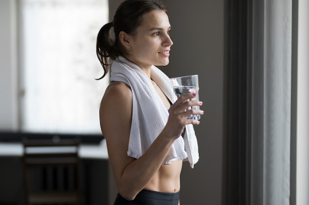 Side view of female with glass of water and towel over shoulders