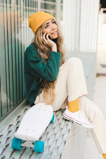 Side view female with skateboard talking over phone