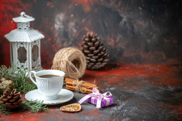 Foto gratuita vista laterale dei rami di abete lime cannella cono di conifere una palla di corda una tazza di tè nero su sfondo rosso