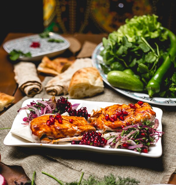 Side view fish kebab on pita bread with pomegranate and onion with herbs