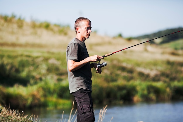 Side view of a fisherman holding fishing rod