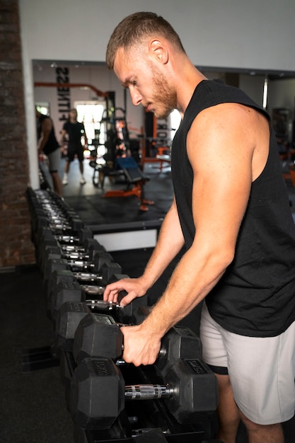 Side view fit man holding dumbbells