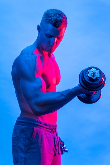 Side view of fit shirtless man with weights