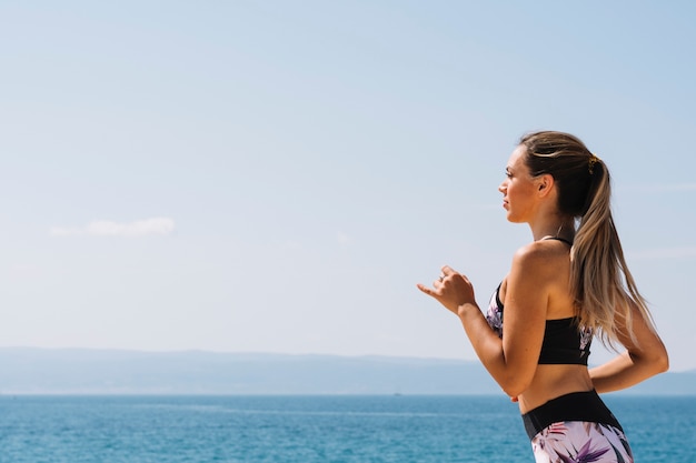 Side view of a fitness young woman running in front of sea