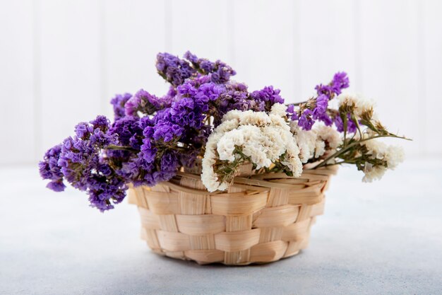 Side view of flowers in basket on white surface