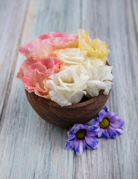 Side view of flowers in bowl and on wooden background