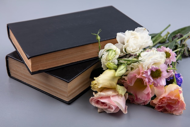 Side view of flowers and closed books on gray background