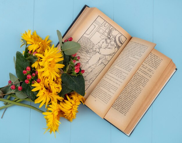 Side view of flowers on open book on blue surface