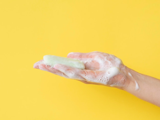 Вид сбоку пенной руки, держащей мыло