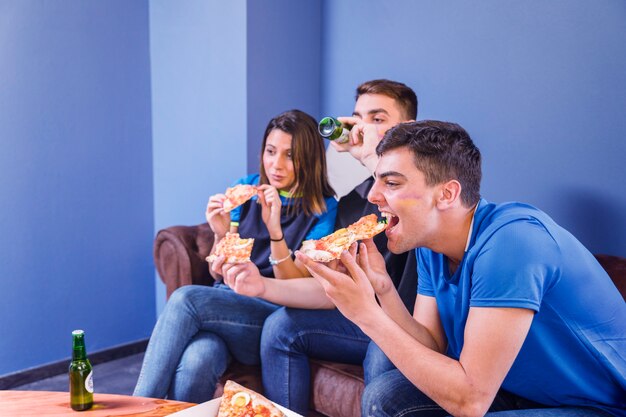 Side view of football fans on couch