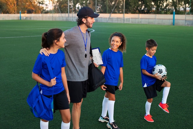 Free photo side view football trainer teaching kids