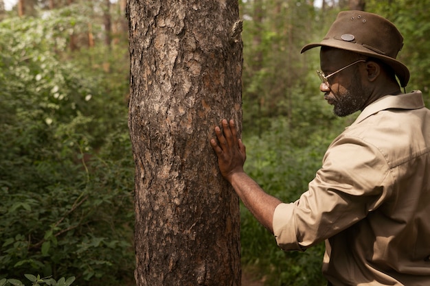 Free photo side view forest warden looking at tree