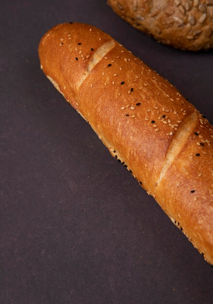 Side view of french baguette on maroon background with copy space