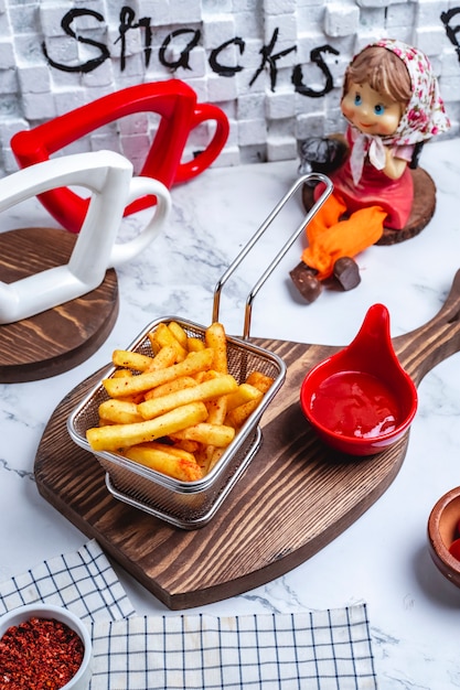 Side view french fries in a basket with ketchup on the board