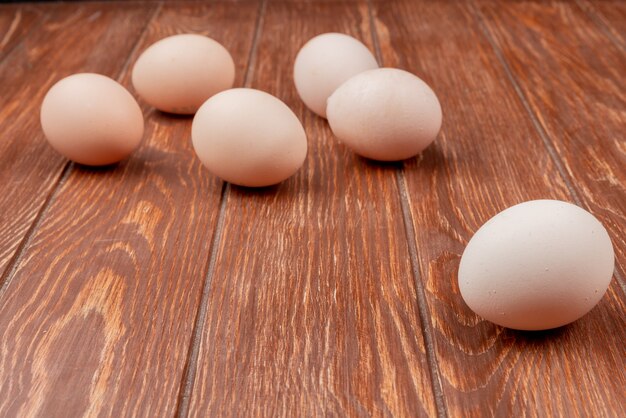 Side view of fresh chicken eggs isolated on a wooden background