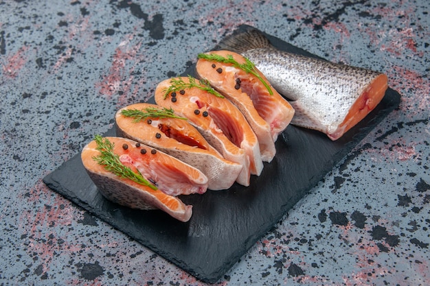 Free photo side view of fresh cut raw fishes green on dark color tray on blue black mix colors table with free space