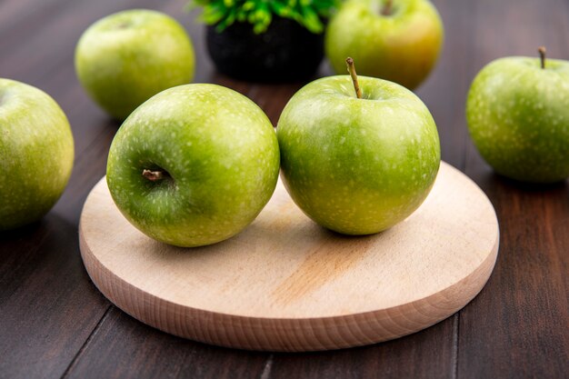 Side view of fresh and green apples on a wooden kitchen board on a wooden surface