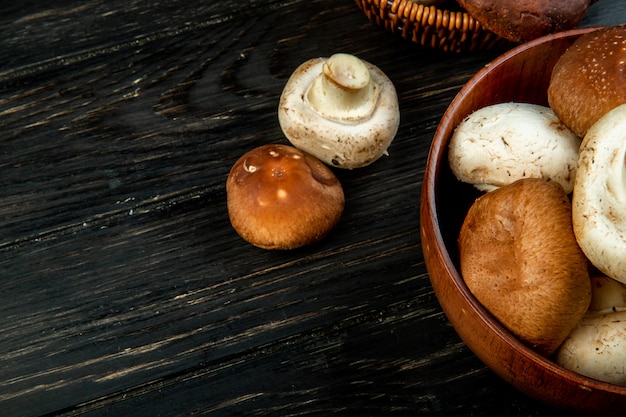 Side view of fresh mushrooms in a bowl on dark wood with copy space