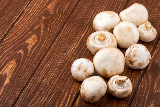 Side view of fresh mushrooms champignon on wooden background