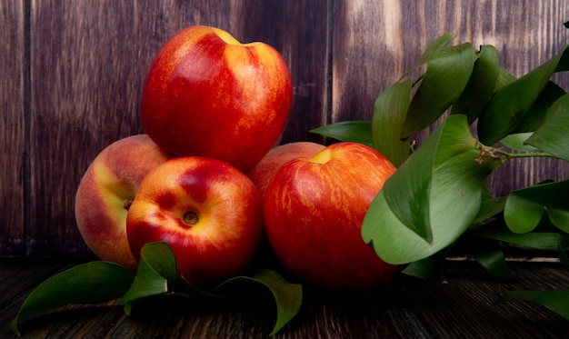 Side view of fresh ripe nectarines with green leaves on rustic wood