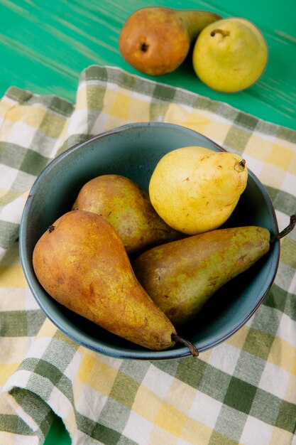 Side view of fresh ripe pears in a bowl on green wooden background