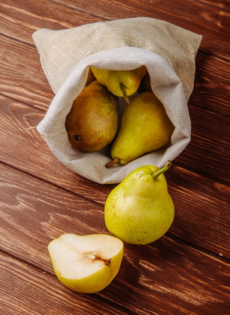 Free photo side view of fresh ripe pears in a sack on a wooden background