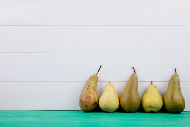 コピースペースを持つ白い木製の背景に新鮮な熟した梨の側面図