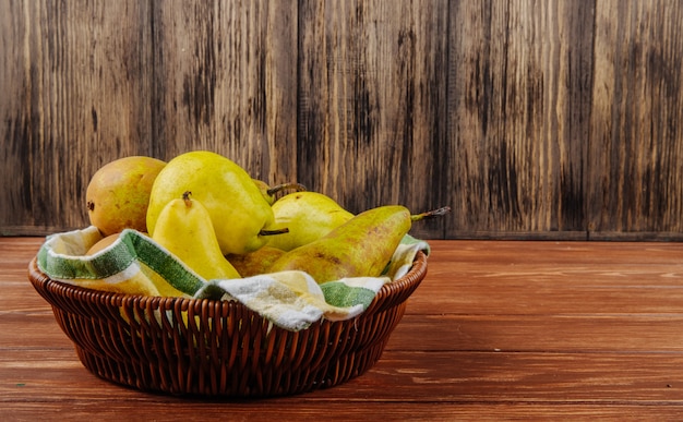 Free photo side view of fresh ripe pears in a wicker basket on a wooden background