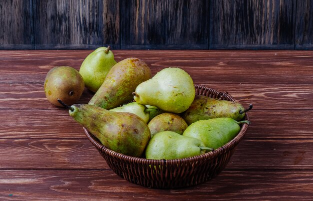 Side view of fresh ripe pears in a wicker basket on a wooden background