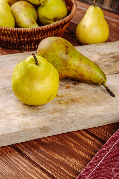 Foto gratuita vista laterale di pere mature fresche su un tagliere di legno