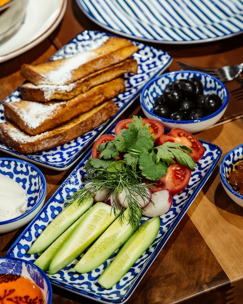 오이 허브와 토마토와 신선한 샐러드의 측면보기 토스트와 블랙 올리브와 함께 제공